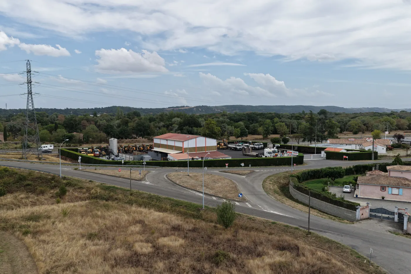 Photo aérienne oblique d'un dépôt d'engins de chantier en bordure d'autoroute